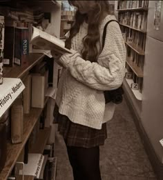 a woman standing in a bookstore reading a book