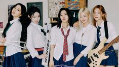 four girls in school uniforms are posing with guitars