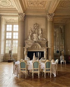 the dining room is decorated in white and gold with blue chairs, table cloths, and an ornate fireplace