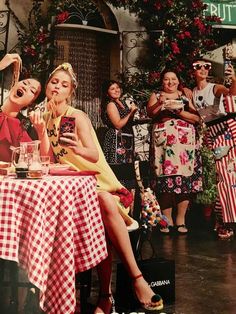 two women sitting at a table in front of a group of people taking pictures with their cell phones