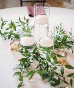 candles and greenery are arranged on the table