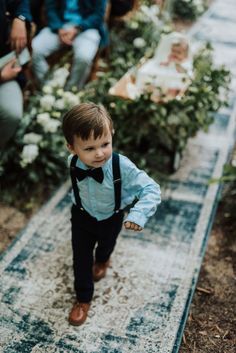 a little boy walking down the aisle at a wedding