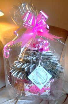 a clear plastic bag filled with cookies and pink ribbon tied around the top, sitting on a couch