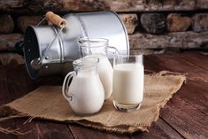 two glasses of milk sitting next to a metal pail