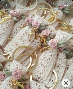 several pairs of gold rings with pink flowers and leaves on them, all surrounded by crocheted lace