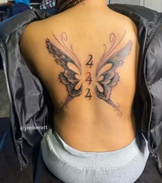 the back of a woman's tattoo with two butterflies on her upper and lower back