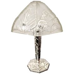 a glass table lamp with an intricate design on the top and bottom, sitting against a white background