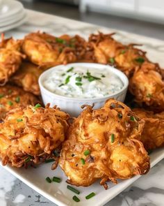 some fried food on a white plate with dip