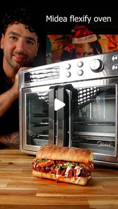 a man standing next to a toaster oven with a sandwich in front of it