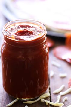 a jar filled with sauce sitting on top of a wooden table