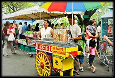 a man and woman standing next to a cart with food on it