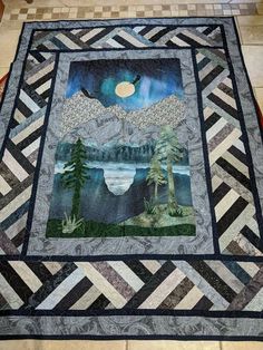 a quilted table runner with mountains and trees in the background, on a tile floor