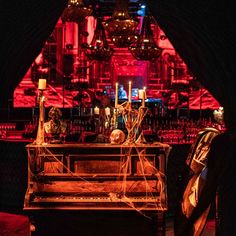 an old piano with candles on it in front of a red lit bar and chandelier