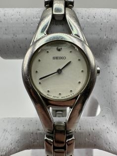 This vintage Seiko 1N00 ladies silver watch exudes retro charm with its classic design, featuring a white circle face that adds a touch of timeless elegance. Perfect as a gift for her or as a personal indulgence, this watch is a testament to both designer fashion and enduring style. Fitted with a new battery and running smoothly, it offers reliable performance for its wearer. Though the glass may have scratches, its stainless steel construction ensures durability for years to come. With a size t Vintage White Round Watches, Circle Face, White Circle, Retro Mode, Women Wrist Watch, Small Gift, Steel Construction, Silver Watch, Small Gifts