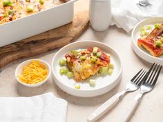 a table topped with plates and bowls filled with food next to a casserole dish