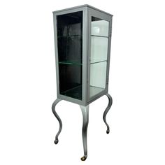 a glass display cabinet sitting on top of a metal stand with two shelves in it