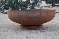 a large metal bowl sitting on top of a grass covered field