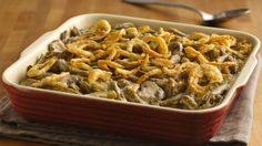 a casserole dish filled with green beans and onion rings on a wooden table