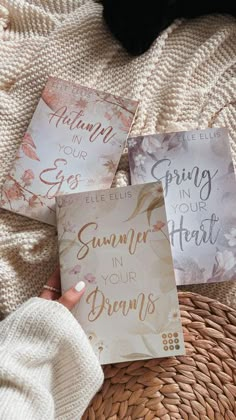 three cards with the words spring and summer in gold lettering on them, sitting on a wicker basket