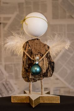 a wooden figurine with a white ball on it's head and some feathers around its neck