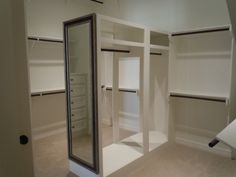 an empty walk in closet with white walls and shelves on each side, including mirror