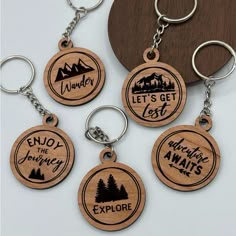 four wooden keychains with the words wander, let's get lost and explore