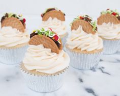 some cupcakes with white frosting and strawberries on top are sitting on a marble surface