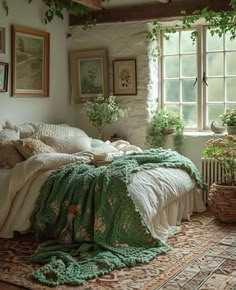 a bed sitting in a bedroom next to a window covered in green blankets and pillows