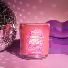 a pink candle sitting next to a disco ball