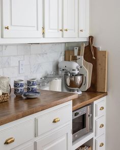 a kitchen with white cabinets and wooden counter tops, including an open drawer for cooking utensils