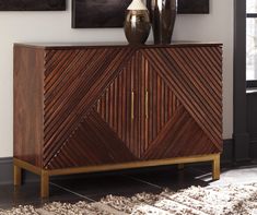 a wooden cabinet with two vases sitting on it's sideboard in a room