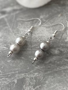 Add a touch of elegance to your wardrobe with these timeless earrings. Handmade with love to elevate any look. Sterling silver ear hook with faux pastel grey pearl drop. Pearls are 8mm in size.  Free shipping to UK buyers. I dispatch within 1-3 days but aim for next day postage with Royal Mail.  Presented on a gift card and wrapped beautifully in luxury tissue and a lovely organza bag to make these the perfect gifts.  Customer satisfaction is my main priority so if  you are not completely in LOVE with your purchase, please let me know and you'll receive a stress free refund. These are perfect for any occasion or outfit. perfect for bridesmaid outfits or as gifts.  Thank you for viewing. Please ask any questions, I am always available to help.  I have plenty of pieces in my shop so please s Pearl Silver Earrings, Bridesmaid Outfits, Timeless Earrings, Pastel Grey, Silver Pearl Earrings, Pearl Grey, Ear Hook, Matching Bracelets, Earrings Sterling Silver