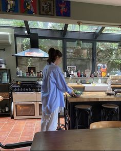 a woman standing in a kitchen preparing food on top of a counter next to an oven