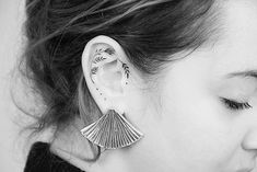 a close up of a person wearing some kind of earring with leaves on it