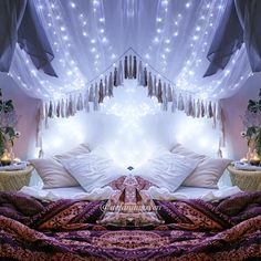 a bed with white sheets and lights hanging from the ceiling