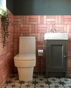 a white toilet sitting next to a sink in a room with tiled walls and floor