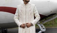 a man standing in front of an airplane with his hands on his hips and looking at the camera