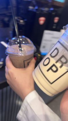 two people are holding cups with drinks in them and one person is holding a straw