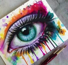 an eye painted on paper with watercolors and paintbrushes next to it