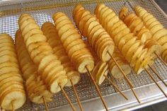 several skewered potatoes on a metal tray in front of an open stove top