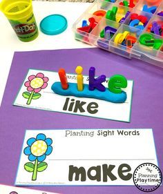 some sort of sight words that are on a purple table with plastic containers and flowers