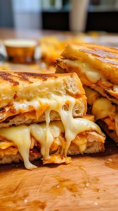 two grilled cheese sandwiches sitting on top of a wooden cutting board with melted cheese