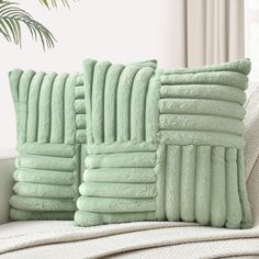 two green pillows sitting on top of a white couch