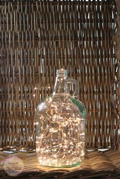 a lighted glass bottle sitting on top of a wicker basket