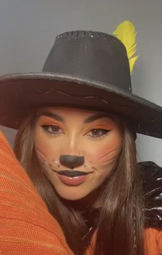 a woman wearing a cat costume and a black hat with yellow feathers on her nose