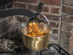 a pot filled with food sitting on top of a stove next to a brick wall