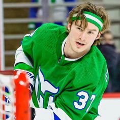 a young man in green jersey skating on ice