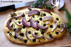 an onion and olive pizza on a cutting board