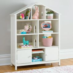 a white doll house shelf with books and toys