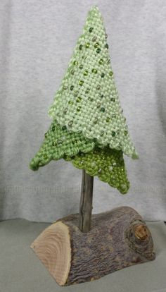 a small knitted christmas tree sitting on top of a piece of wood